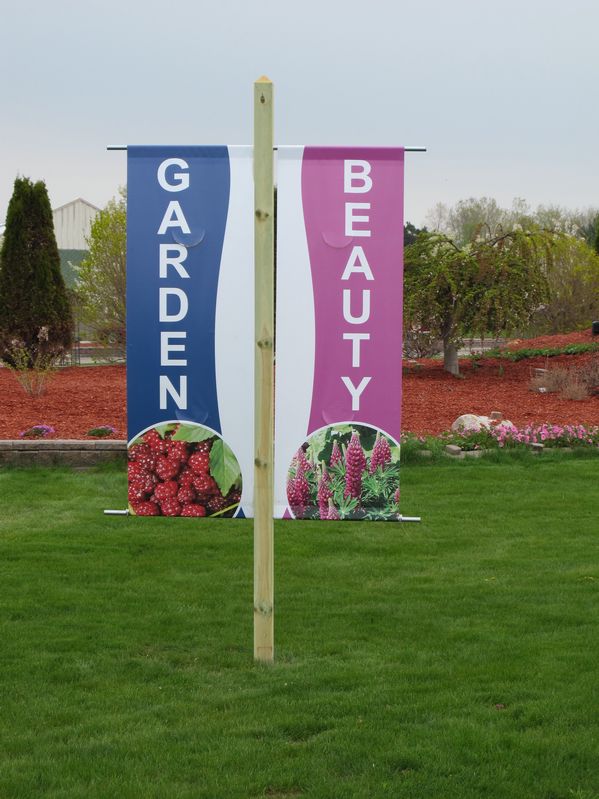 Large, easy-to-read roadside banners for Garden Crossings in Zeeland, MI get drivers' attention. There are four banners and each one has a different plant picture to show a variety of plants offered.